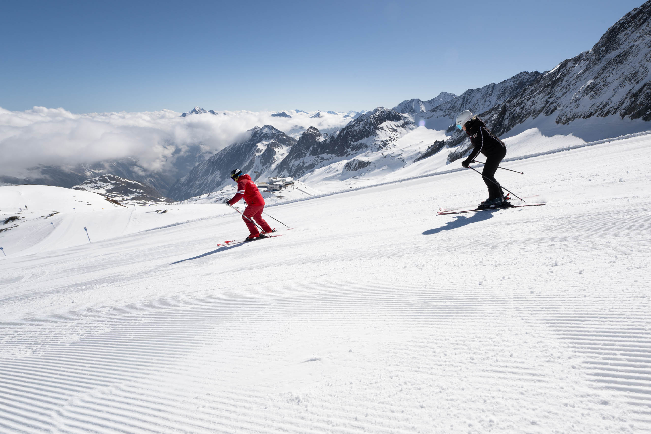 Ein Schneesportlehrer fährt einer Schi-Schülerin vor