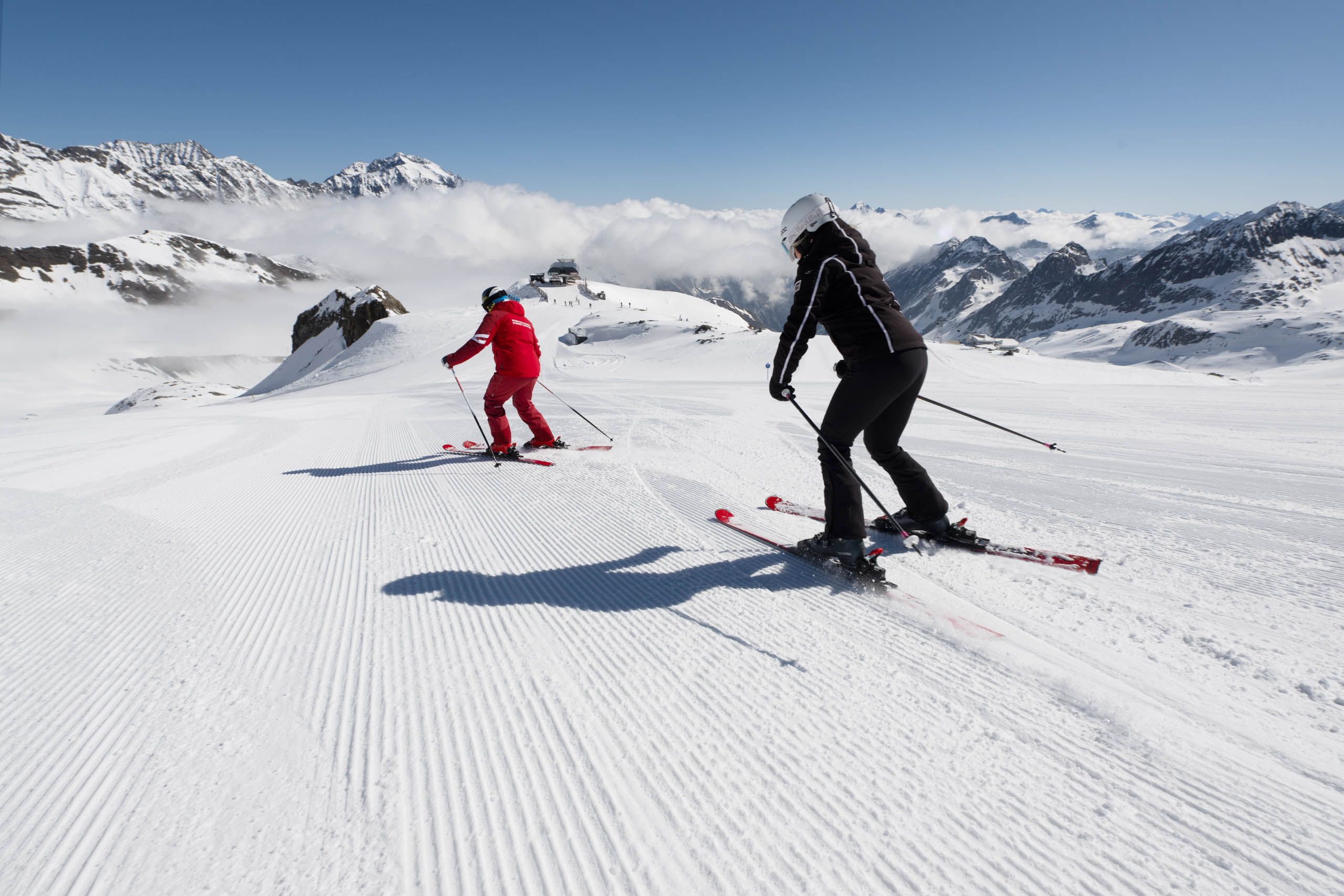 Ein Schneesportlehrer fährt einer Schi-Schülerin vor
